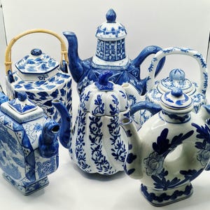 May include: A collection of six blue and white ceramic teapots. The teapots vary in shape and design, including floral patterns, geometric shapes, and bamboo handles. The teapots are displayed against a white background.