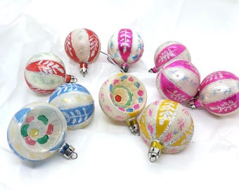 May include: A collection of vintage Christmas ornaments in various colors. The ornaments are round with silver caps and feature designs in red, pink, blue, and yellow. Some have stripes, while others have floral or geometric patterns.
