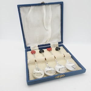 May include: Set of four silver teaspoons with red and black heart-shaped handles in a blue velvet box.