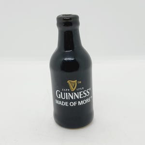 May include: A black ceramic bottle with a gold Guinness logo and the text "ESTD 1759 TM GUINNESS MADE OF MORE".