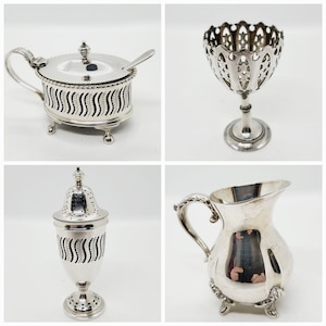 May include: Four silver serving pieces, including a sugar bowl, a creamer, a salt cellar, and a small bowl with a decorative handle.