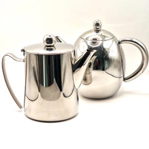 May include: A trio of ceramic mugs with a speckled, matte finish in cream, light brown, and dark brown. Each mug features a minimalist design and a rounded handle.