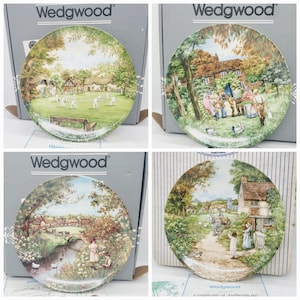 Peut inclure: Quatre assiettes en porcelaine fine Wedgwood avec un fond blanc et une image colorée d'une scène de village. Les assiettes sont dans leurs boîtes d'origine. Les boîtes sont blanches avec le logo Wedgwood imprimé dessus.