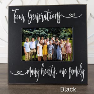 May include: Black picture frame with the text "Four Generations, many hearts, one family" in white lettering. The frame has a photo of a large family group.