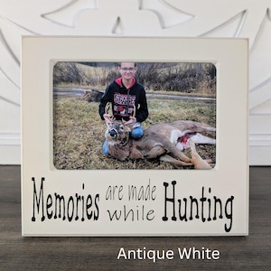 May include: White picture frame with a photo of a person posing with a deer. The frame has the text "Memories are made while Hunting" and "Antique White" printed on it.