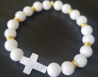 Op de afbeelding: Witte kralen armband met gouden accenten en een witte kruis hanger.