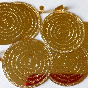 May include: Six gold-colored round pendants with intricate circular designs and a small loop at the top for hanging.