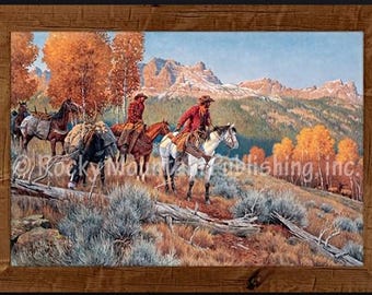 May include: A framed landscape painting depicting two riders on horseback and a pack horse travelling through a mountain range during autumn. The scene features golden trees, sagebrush, and rocky peaks. The text Rocky Mountain Publishing, inc. is visible.