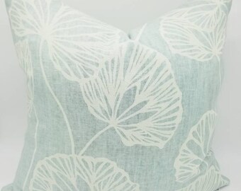 May include: A light blue throw pillow with a white leaf pattern. The pillow is made of a soft, textured fabric.