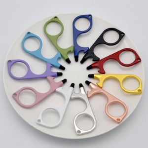 May include: A set of 12 multi-colored metal door openers with a bottle opener feature. The openers are arranged in a circle on a white plate.