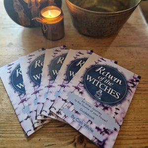 May include: A stack of five purple and white guidebooks titled "Return of the Witches: An Inner Journey to the Source of your Power! Guidebook by Cali White."