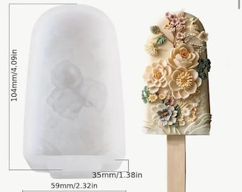 May include: White silicone mold for making popsicles or ice pops. The mold is shaped like a popsicle and has a floral design. The mold is 4.09 inches tall, 2.32 inches wide, and 1.38 inches deep.