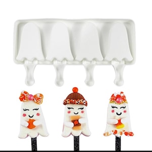 May include: A white silicone mold with four ghost-shaped cavities for making popsicles. The mold has a handle on each cavity. Three decorated ghost popsicles are shown in front of the mold.