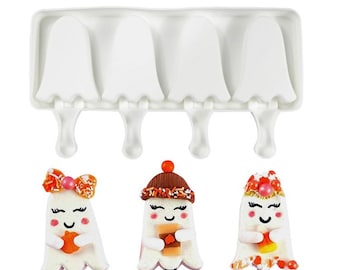 May include: A white silicone mold with four ghost-shaped cavities for making popsicles. The mold has a handle on each cavity. Three decorated ghost popsicles are shown in front of the mold.