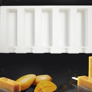 May include: White silicone popsicle mold with six individual slots. The mold is on a black surface with mango slices and a popsicle.