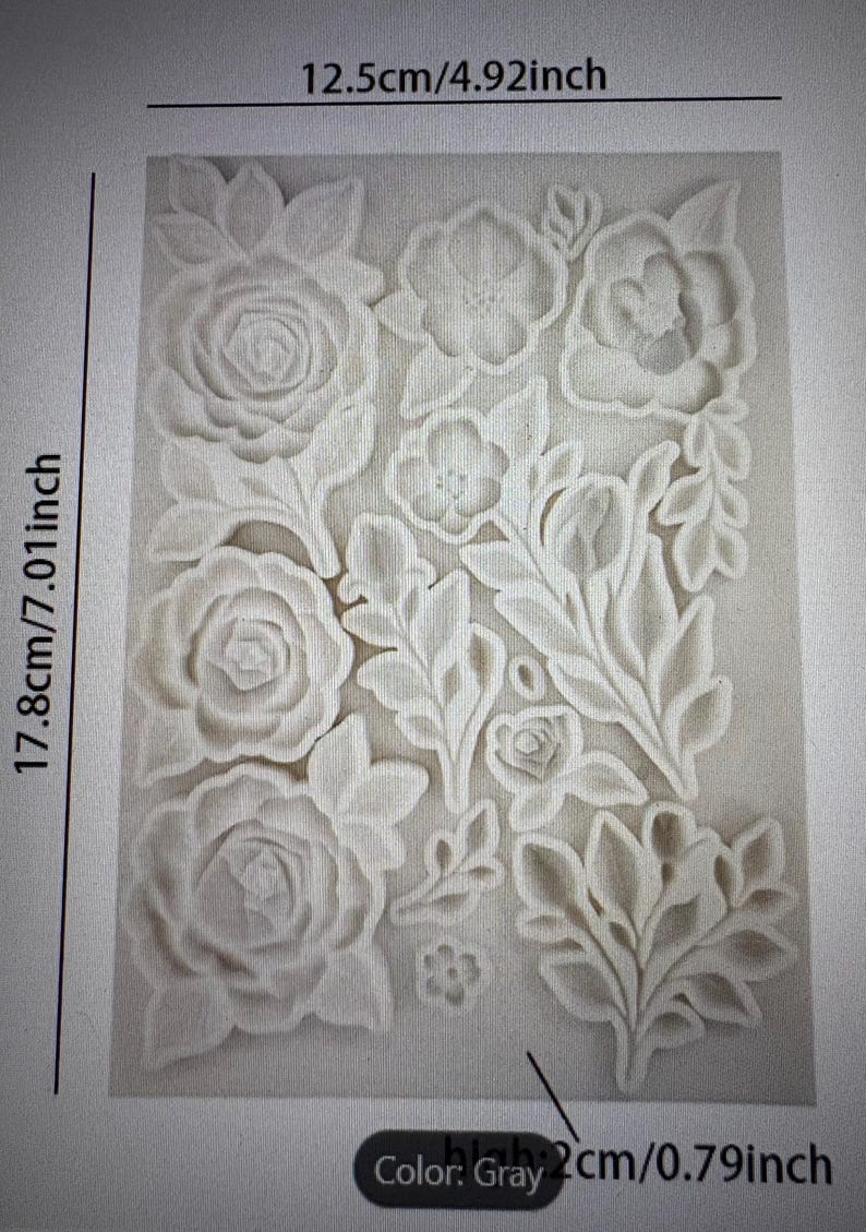 Peut inclure: Moule en silicone floral gris, de 17,8 cm de haut, 12,5 cm de large et 2 cm d'&eacute;paisseur. Le moule pr&eacute;sente une vari&eacute;t&eacute; de fleurs et de feuilles en relief. La couleur est grise.