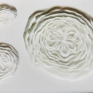 May include: White silicone mould with three different sized circular impressions. The impressions are designed to create a flower shape with multiple layers of petals.