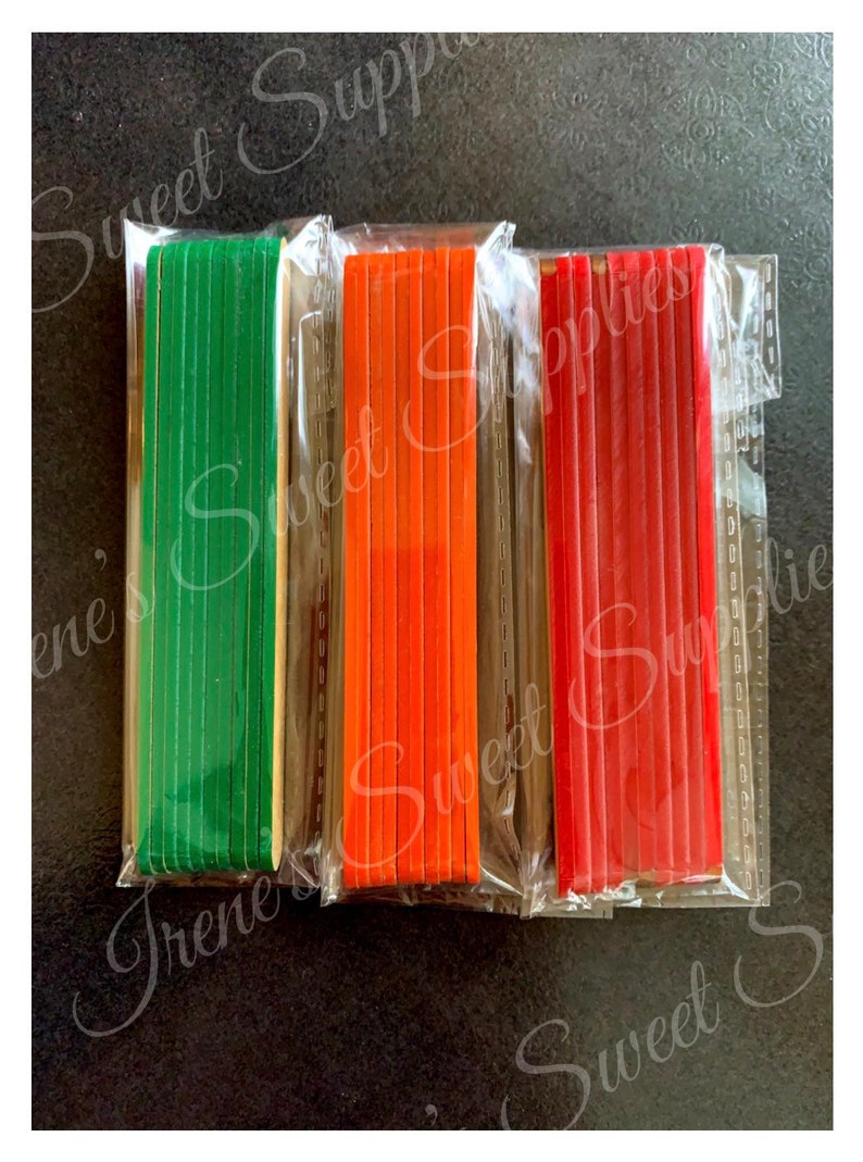 May include: Three packs of wooden craft sticks, each pack containing 10 sticks. The sticks are wrapped in clear plastic and are green, orange, and red.
