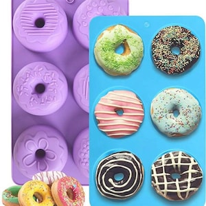 May include: Two silicone donut baking molds. One mold is purple and has six donut cavities. The other mold is blue and has six donut cavities. The blue mold has donuts with different toppings in each cavity.
