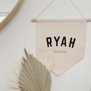May include: A white canvas banner with the name "RYAH SLOANE" printed in black block letters.
