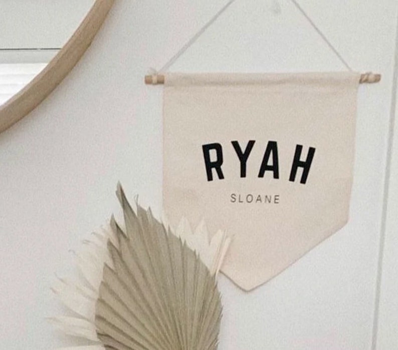 May include: A white canvas banner with the name "RYAH SLOANE" printed in black block letters.