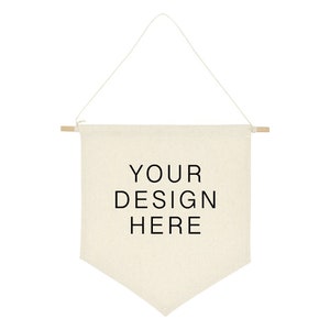May include: A blank canvas banner with wooden dowels at the top and a rope hanger. The banner is beige and has the text "YOUR DESIGN HERE" printed in black.