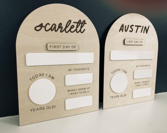 May include: Two wooden signs with arched tops, one for Scarlett and one for Austin. Each sign has blank spaces for writing in the first or last day of school, teacher's name, age, and what they want to be when they grow up.