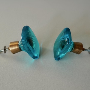 Peut inclure: Deux boutons de cabinet en verre bleu turquoise avec des tiges en laiton et des vis argentées.