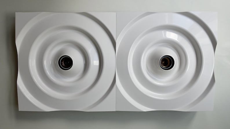 Puede incluir: Dos l&aacute;mparas de pared cuadradas blancas con un dise&ntilde;o circular empotrado y una sola bombilla en cada una.