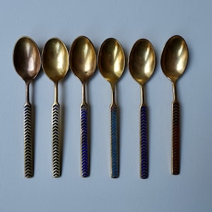 May include: Six gold teaspoons with blue and black enamel handles. The handles have a chevron pattern.