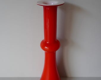 Op de afbeelding: Een hoge, oranje glazen vaas met een witte rand. De vaas heeft een bolvormig middengedeelte en een uitlopende basis.