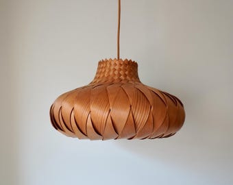 May include: A woven wood pendant light fixture with a brown finish. The light fixture has a round, bowl-shaped shade.
