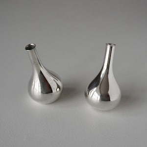 Op de afbeelding: Twee zilveren, peer-vormige vaasjes.
