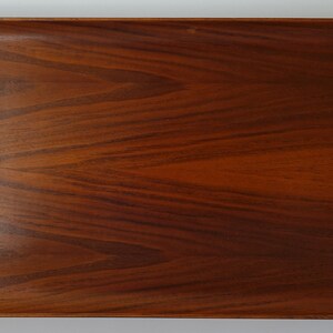 May include: A rectangular wooden serving tray with rounded edges and a rich brown color. The tray has a smooth, polished surface and a natural wood grain pattern.