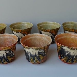 Könnte beinhalten: Satz von acht kleinen, cremefarbenen Keramik-Blumentöpfen mit einer schwarzen und weißen Grafik eines Pferdes auf gelbem, orangefarbenem und grünem Hintergrund.