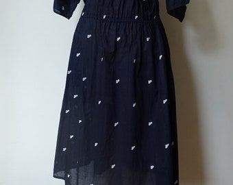 May include: A navy blue dress with a white heart pattern. The dress has a gathered waist and short sleeves.