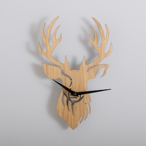 May include: A wooden wall clock shaped like a deer head with black clock hands.