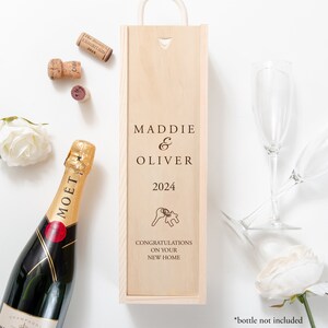 Puede incluir: Caja de madera para vino con un mensaje personalizado para una nueva casa. La caja está grabada con los nombres Maddie & Oliver, el año 2024 y el texto "Felicidades por su nueva casa".