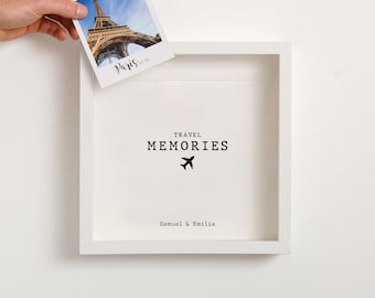 May include: White square frame with a white mat and a black and white photo of the Eiffel Tower in Paris. The frame has the text "TRAVEL MEMORIES" with a small airplane icon and the names "Samuel & Emilia" below.