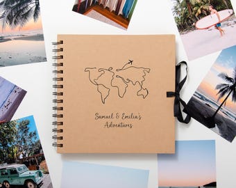 Könnte beinhalten: Ein braunes Fotoalbum mit einem schwarzen Band und einer Weltkartenillustration. Der Text "Samuel & Emilia's Adventures" ist auf dem Cover gedruckt.