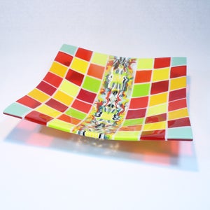May include: A square glass dish with a checkered pattern in red, yellow, and green. The dish has a wavy, organic design in the center.