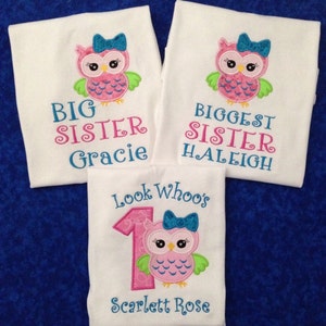 Puede incluir: Tres camisetas blancas con bordado de b&uacute;ho rosa y verde. La camiseta de arriba dice "Big Sister Gracie". La camiseta del medio dice "Biggest Sister  Haleigh". La camiseta de abajo dice "Look Who's 1 Scarlett Rose".