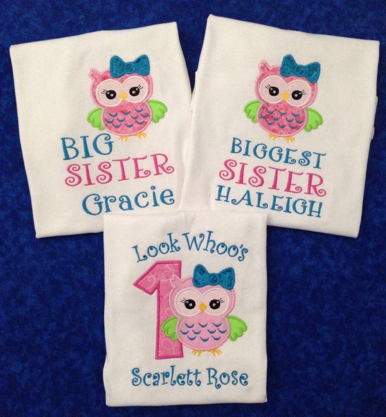 Puede incluir: Tres camisetas blancas con bordado de b&uacute;ho rosa y verde. La camiseta de arriba dice "Big Sister Gracie". La camiseta del medio dice "Biggest Sister  Haleigh". La camiseta de abajo dice "Look Who's 1 Scarlett Rose".