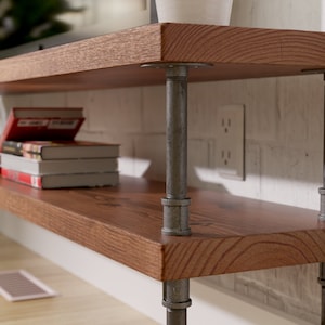 Puede incluir: Dos estantes de madera sostenidos por patas de tuber&iacute;a industrial. Los estantes son de madera marr&oacute;n oscura con un patr&oacute;n de veta natural. Las tuber&iacute;as est&aacute;n pintadas de color gris oscuro. Los estantes est&aacute;n montados en una pared de ladrillo blanco.