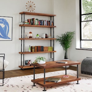 May include: A rustic wooden bookshelf with black metal pipes, featuring five shelves filled with books, decorative items, and plants. The bookshelf is in a living room setting with a coffee table, a rug, and a window.