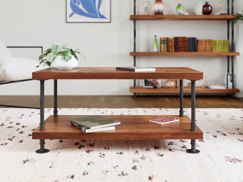 May include: A two-tiered coffee table with a rustic wood top and black metal pipe legs. The table has a lower shelf for storage and is sitting on a white rug.