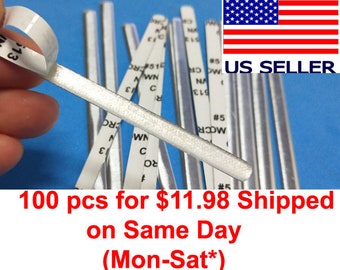May include: A close-up of several silver-colored nose bridge strips with adhesive backing. The image includes the text "US SELLER" and the American flag. The text "100 pcs" is also visible.