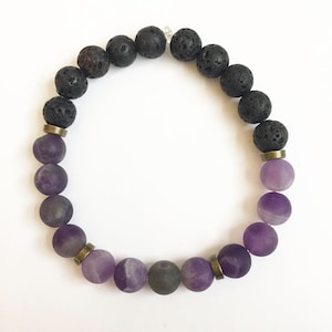 May include: A beaded bracelet with black lava rock beads and purple amethyst beads. The bracelet has gold-toned metal spacers between the beads.
