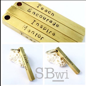 May include: Gold-toned metal keychain with a rectangular charm engraved with the words "Teach, Encourage, Inspire, Mentor".