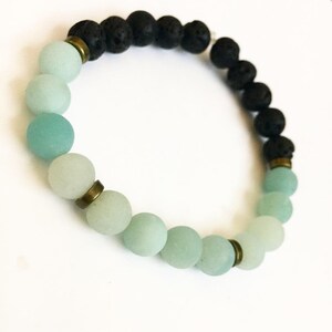 May include: A bracelet with black lava rock beads and light green agate beads. The beads are separated by gold-toned spacers.